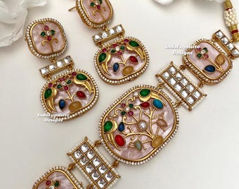 May include: A gold-toned jewelry set featuring a necklace and earrings. The set has pink, oval-shaped pendants with colorful floral designs and clear stone accents. The earrings are studs and drop earrings. The necklace has a matching pendant and square accents.