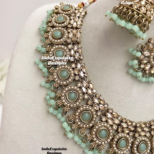 May include: A gold and silver necklace with light blue stones and pearl accents. The necklace is part of a set that includes matching earrings.