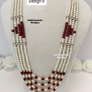 May include: A multi-strand necklace with white faux pearls and burgundy beads. The necklace has gold-colored accents and rhinestone-studded bars. The text "Design 5" and "IndoExquisite Designs" are visible.