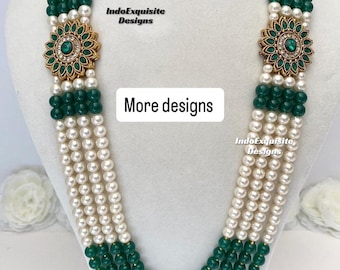 May include: A multi-strand necklace featuring white faux pearls and green beads. The necklace has a floral pendant with green gemstones and gold-colored accents. The text "Design 1" and "More designs" are visible.
