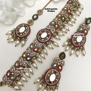 Peut inclure: Un ensemble de collier et boucles d'oreilles en or avec un motif miroir. Le collier est de style ras de cou avec une rangée de perles et les boucles d'oreilles sont de forme goutte avec des perles qui pendent du bas.