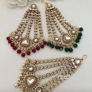May include: Three gold-tone headpieces with pearl and green or red beads. The headpieces have a heart-shaped design with a clear stone in the center. The text "IndoExquisite Designs" is visible on the headpieces.