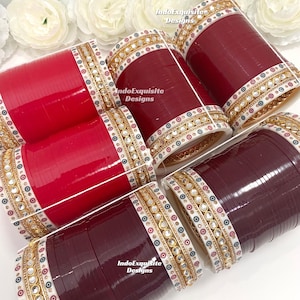 Può includere: Una collezione di braccialetti rossi e bordeaux con intricati dettagli dorati e bianchi. I braccialetti presentano un motivo di piccoli specchi e accenti dorati. L'immagine include il testo "IndoExquisite Designs".