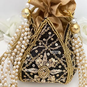 Könnte beinhalten: Eine schwarze und goldene Perlen-Kordeltasche mit einem goldenen Quasten und Perlen-Akzenten. Die Tasche ist mit aufwendigen Stickereien und Pailletten verziert.