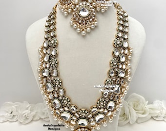 Op de afbeelding: Een gouden ketting en oorbellen set met groene en witte stenen en parels. De ketting heeft een grote hanger met een groene en witte steen.
