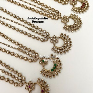 Może przedstawiać: Kilka złotych nakryć głowy z wiszącymi łańcuszkami i ozdobnymi wisiorkami w kształcie półksiężyca. Każdy wisiorek ma inny kolor kamienia szlachetnego, w tym czerwone, zielone i przezroczyste kamienie. Widoczny jest tekst "IndoExquisite Designs".