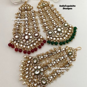 May include: A pair of gold-tone earrings with multiple layers of pearl and mirror-like embellishments. The earrings have green and red beads at the bottom. The text "IndoExquisite Designs" is visible on the image.