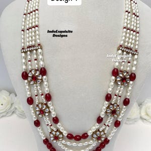 May include: A multi-strand necklace with white pearls and red beads. The necklace features floral-shaped pendants with red stones and gold-colored accents. The text "Design 4" and "IndoExquisite Designs" are visible.