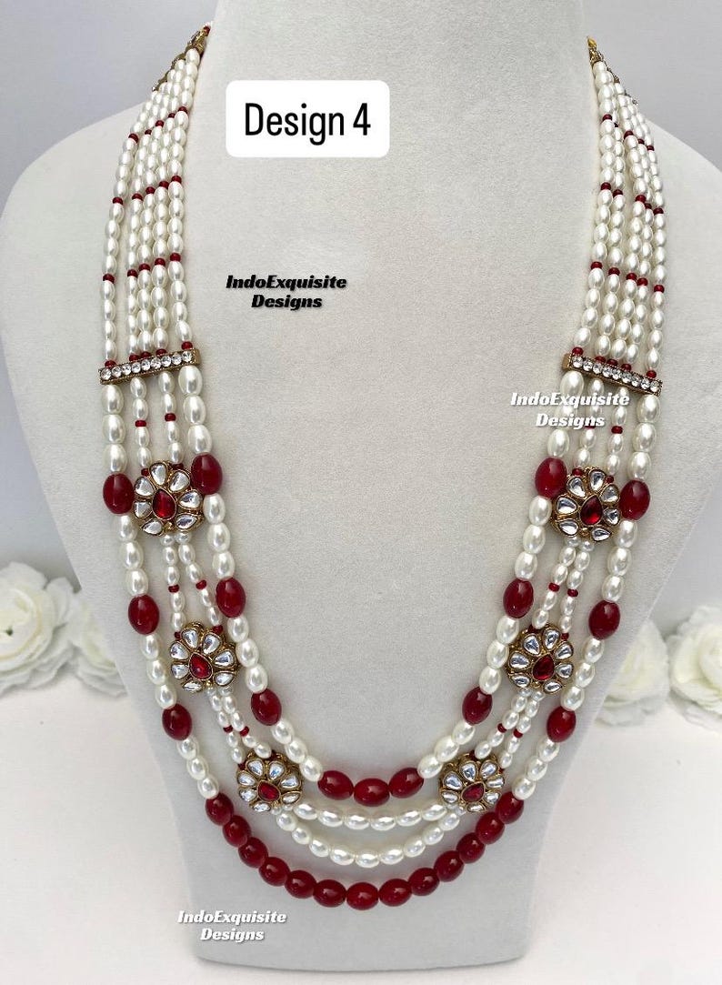 May include: A multi-strand necklace with white pearls and red beads. The necklace features floral-shaped pendants with red stones and gold-colored accents. The text "Design 4" and "IndoExquisite Designs" are visible.