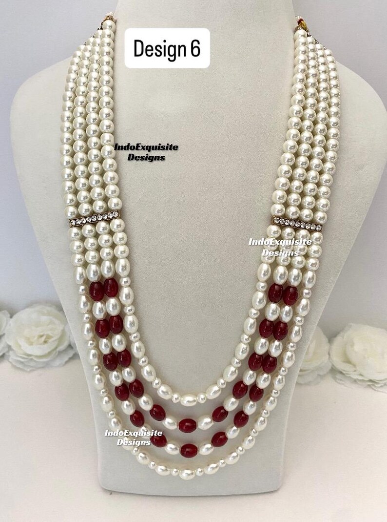 May include: A multi-strand pearl necklace with alternating sections of white pearls and red beads. The necklace has a rhinestone accent and is displayed on a white mannequin. The text "Design 6" is visible.