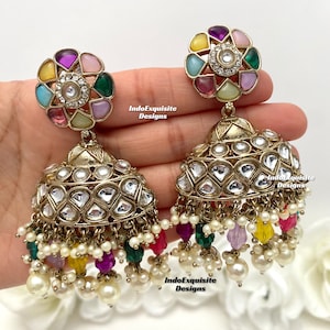 May include: A pair of gold earrings with a multi-coloured stone design and a dangling pearl and crystal fringe. The earrings are called "IndoExquisite Designs".