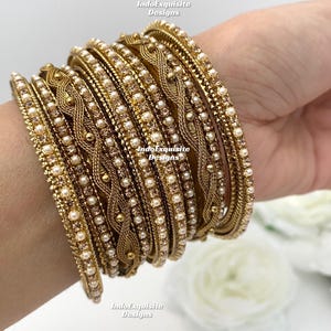 Peut inclure: Un ensemble de bracelets dorés ornés de perles et de strass. Les bracelets sont empilés sur le poignet d'une personne.