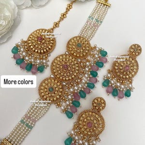 Puede incluir: Un conjunto de joyas en tono dorado que incluye una diadema, un collar y pendientes. Las piezas presentan intrincados diseños circulares con detalles en rosa y verde, y están adornadas con perlas. El texto "More colors" es visible.