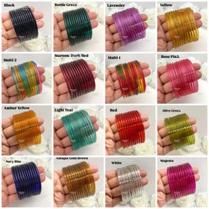 May include: A collection of sixteen sets of thin, translucent glass bangles in various colors including black, bottle green, lavender, yellow, multi-color, maroon, rose pink, amber, light teal, red, olive green, navy blue, antique gold, white, and magenta.