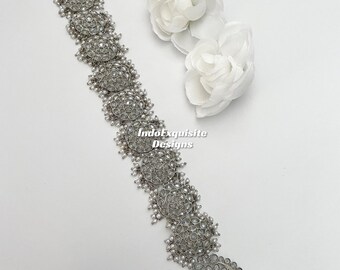 May include: A silver hair chain with pearl accents and a floral design. The chain is made of metal and has a delicate, intricate design. The pearls are white and add a touch of elegance to the piece. The chain is perfect for adding a touch of sparkle to any hairstyle.