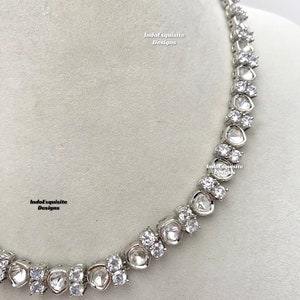 May include: A silver necklace with a row of large, clear, faceted stones. The stones are set in a silver metal setting and are connected by a delicate silver chain. The necklace is a statement piece and would be perfect for a special occasion.