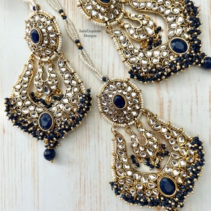 May include: A pair of gold-tone earrings with intricate designs and blue gemstones. The earrings feature a crescent moon shape with a dangling pearl chain.