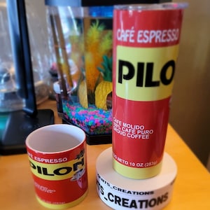 May include: Two red and yellow insulated tumblers with the text "Café Espresso Pilo" and "Café Molido 100% Café Puro Ground Coffee 10 oz (283g)". The tumblers are on a white surface with the text "Gents_Creations" and "TTS_Creations".