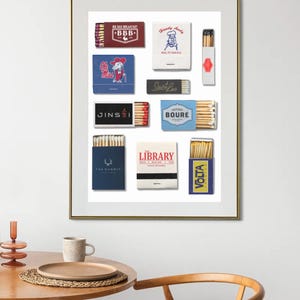 Könnte beinhalten: Ein gerahmter Druck mit verschiedenen Streichholzschachtel-Designs. Die Streichholzschachteln zeigen Logos und Texte, darunter "BBB", "Handy Andy", "Ole Miss", "Saint Leo", "JINSEI", "BOURE", "The Summit", "LIBRARY" und "VOLTA". Der Rahmen ist goldfarben.