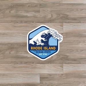 May include: A blue and white sticker with a wave design. The sticker says "Rhode Island, The Ocean State, Est. 1790".