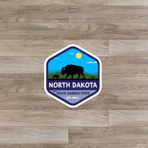 May include: A blue and white hexagonal sticker with a silhouette of a bison and the text "The Peace Garden State - Est. 1867 -" and "North Dakota" in white text.