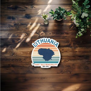 May include: A sticker featuring the word "Lithuania" in a stylized font, with a map of Lithuania in navy blue. The design includes a retro sunset background with orange, tan, and blue stripes. The text "The Fairy Tale Principality - Est. 1719 -" is also included.