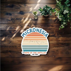 May include: A circular sticker featuring a sunset-inspired gradient of orange, peach, and teal stripes. The text MICRONESIA arches over the top, while The GEMS OF THE ANTILLES - EST. 1986 is printed at the bottom. A small map of islands is centered.