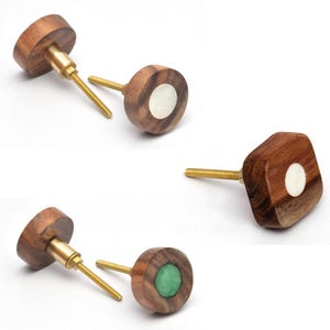 May include: Set of four wooden cabinet knobs with a round or square shape. Each knob features a brass screw and a round inlay of white or green.