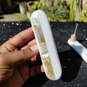 Puede incluir: Un par de tiradores de cajón de concha blanca con incrustaciones de nácar. Los tiradores son de forma rectangular y tienen un acabado liso y pulido.