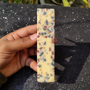 以下が含まれることがあります： 長方形の黄色、白、黒、赤の斑点のあるタイルのクローズアップ。タイルは粗い質感の表面をしています