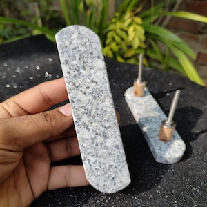 May include: Two granite door handles with a speckled gray and white pattern. The handles are mounted on a metal base with a silver finish.