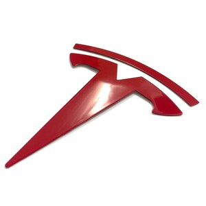 K&ouml;nnte beinhalten: Ein rotes Tesla-Logo, ein stilisiertes T mit einer geschwungenen Linie dar&uuml;ber, ist ein beliebtes Autoemblem.