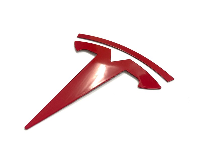 K&ouml;nnte beinhalten: Ein rotes Tesla-Logo, ein stilisiertes T mit einer geschwungenen Linie dar&uuml;ber, ist ein beliebtes Autoemblem.