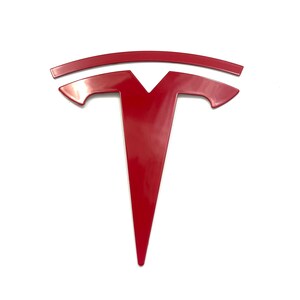 K&ouml;nnte beinhalten: Ein rotes Tesla-Logo, ein stilisiertes T mit einer geschwungenen Linie dar&uuml;ber, ist ein beliebtes Symbol f&uuml;r Elektrofahrzeuge.