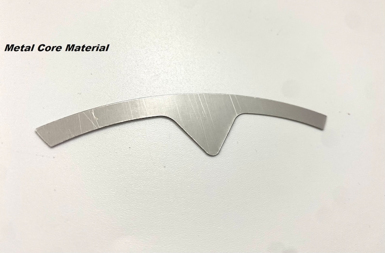 K&ouml;nnte beinhalten: Ein silberfarbenes Metallkernmaterial in Form eines Halbmondes mit einer spitzen Spitze in der Mitte.
