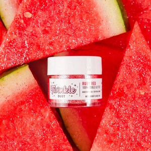 Puede incluir: Un frasco de purpurina comestible "Twinkle Dust" en "Ruby Red" se encuentra entre rodajas de sandía. El frasco tiene una tapa blanca y un cuerpo transparente, mostrando la purpurina roja. La sandía es de color rojo brillante con corteza verde.