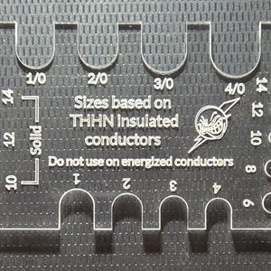 May include: Clear plastic wire gauge tool with markings for THHN insulated conductors. Features sizes 1/0 to 4/0, and wire sizes 6 to 14. Text includes "Sizes based on THHN insulated conductors" and "Do not use on energized conductors."