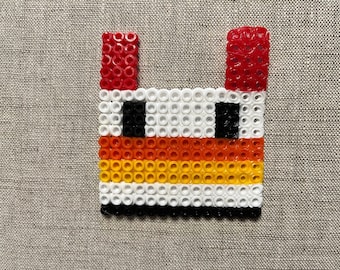 Può includere: Un design di pixel art colorato realizzato con piccole perline di plastica. Il design presenta una combinazione di colori rosso, bianco, nero, arancione e giallo. Le perline sono disposte in una forma rettangolare.
