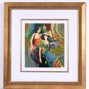 May include: A framed art print featuring two figures in colorful attire. One figure wears a red top and purple skirt, while the other wears a green top, blue skirt, and a hat. The scene includes a floral arrangement and abstract background elements. The artwork is enclosed in a gold-toned frame with a beaded inner border and a white mat.
