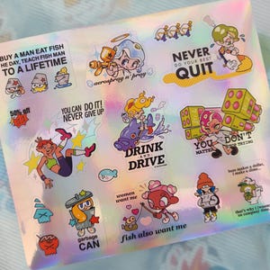 May include: Holographic sticker sheet with various cartoon illustrations and text. Designs include phrases like "Drink and Drive," "Never Quit," and "You Can Do It!" with colorful characters and graphics. The sheet has a rainbow sheen.