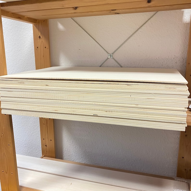 May include: A stack of light brown plywood boards on a wooden shelf.