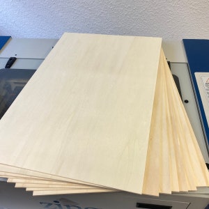 May include: A stack of eight light-colored wood panels. The panels are smooth and have a light wood grain pattern.