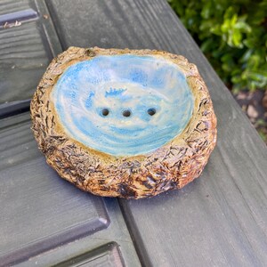Puede incluir: Jabonera de cerámica hecha a mano con un exterior marrón terroso texturizado y un interior azul claro. El interior tiene un patrón arremolinado y tres orificios de drenaje. Un accesorio de baño rústico y único.
