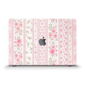Peut inclure: Une coque d'ordinateur portable avec un motif floral de roses roses et de feuilles vertes sur fond blanc. Le design comprend des rayures verticales avec des motifs de dentelle. Le logo Apple est visible au centre.