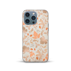 Può includere: Una custodia per telefono trasparente con un motivo di foglie arancioni e marroni su sfondo bianco. La custodia è progettata per un iPhone con una fotocamera a tre obiettivi.