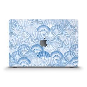 May include: A blue and white laptop skin with a pattern of seashells. The skin is designed to fit a MacBook.
