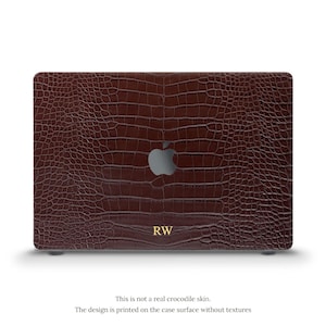 May include: A dark brown laptop case featuring a printed crocodile skin pattern. The center displays a silver Apple logo, and the bottom center features the gold-colored initials RW. The text states this is not real skin and is printed without texture.