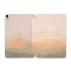 Puede incluir: Un fondo de acuarela rosa y naranja con una cruz en la cima de una montaña. El texto "Ya no soy yo quien vive, sino Cristo quien vive en mí. Gálatas 2:20" está escrito en blanco en el lado derecho de la imagen.