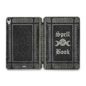 Peut inclure: Un livre relié en cuir noir avec un motif en relief argenté. Le titre du livre est "Spell Book" avec un pentagramme argenté et un symbole de croissant de lune.