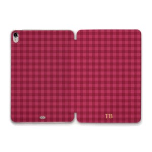 Può includere: Custodia per tablet a quadri bordeaux e rosa scuro, aperta per mostrare l'interno. La custodia ha una chiusura a scatto e un'apertura per la fotocamera. Le iniziali "TB" sono in oro nell'angolo in basso a destra.